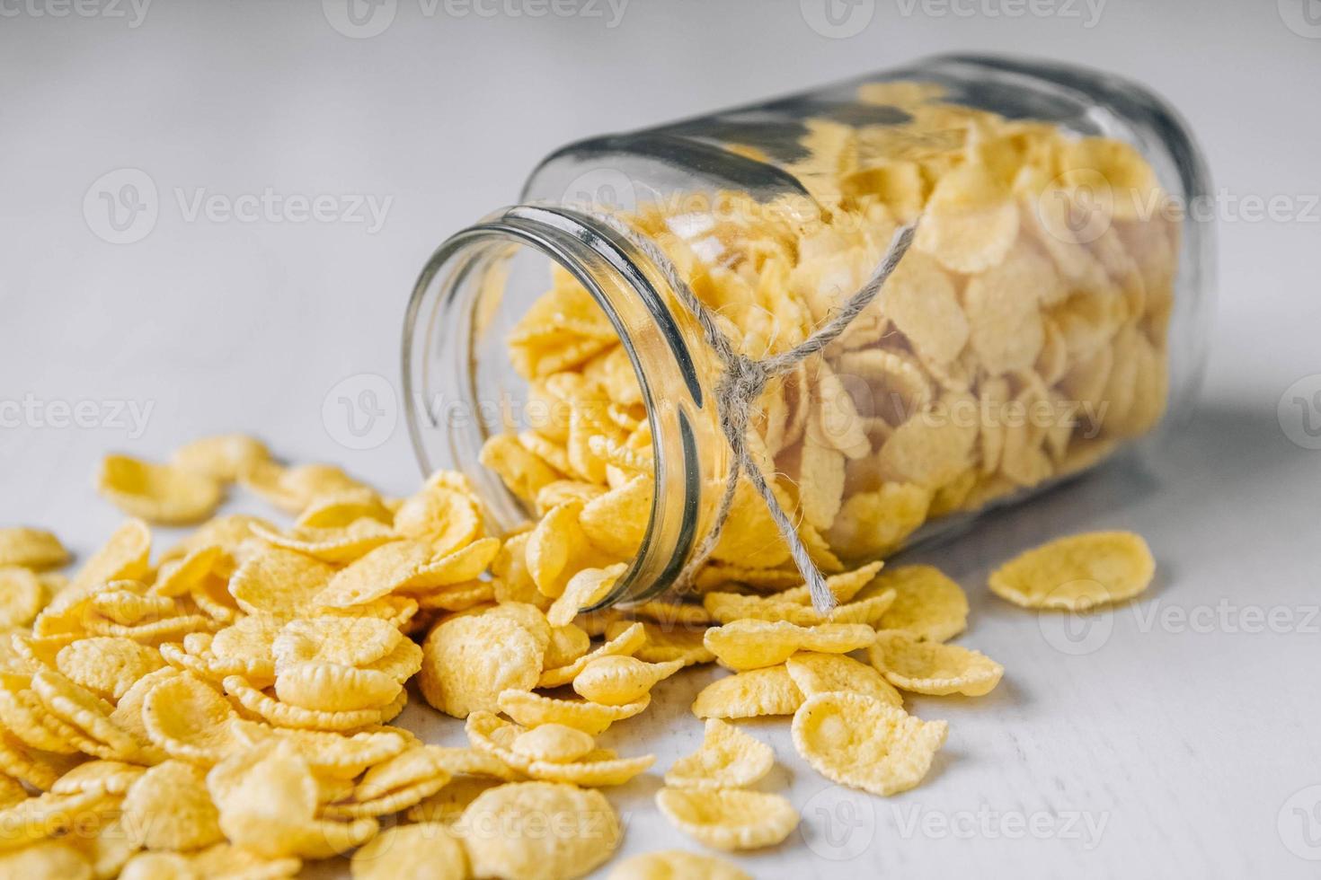 flocos de milho em uma jarra de vidro na superfície de madeira branca foto
