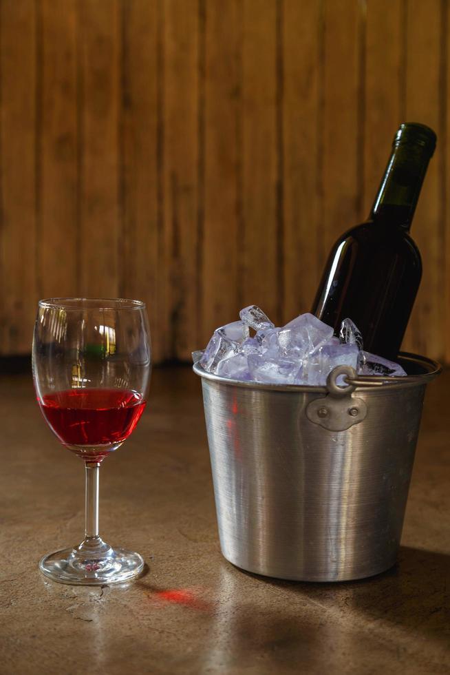 garrafa de vinho tinto em um balde de gelo e uma taça de vinho tinto foto