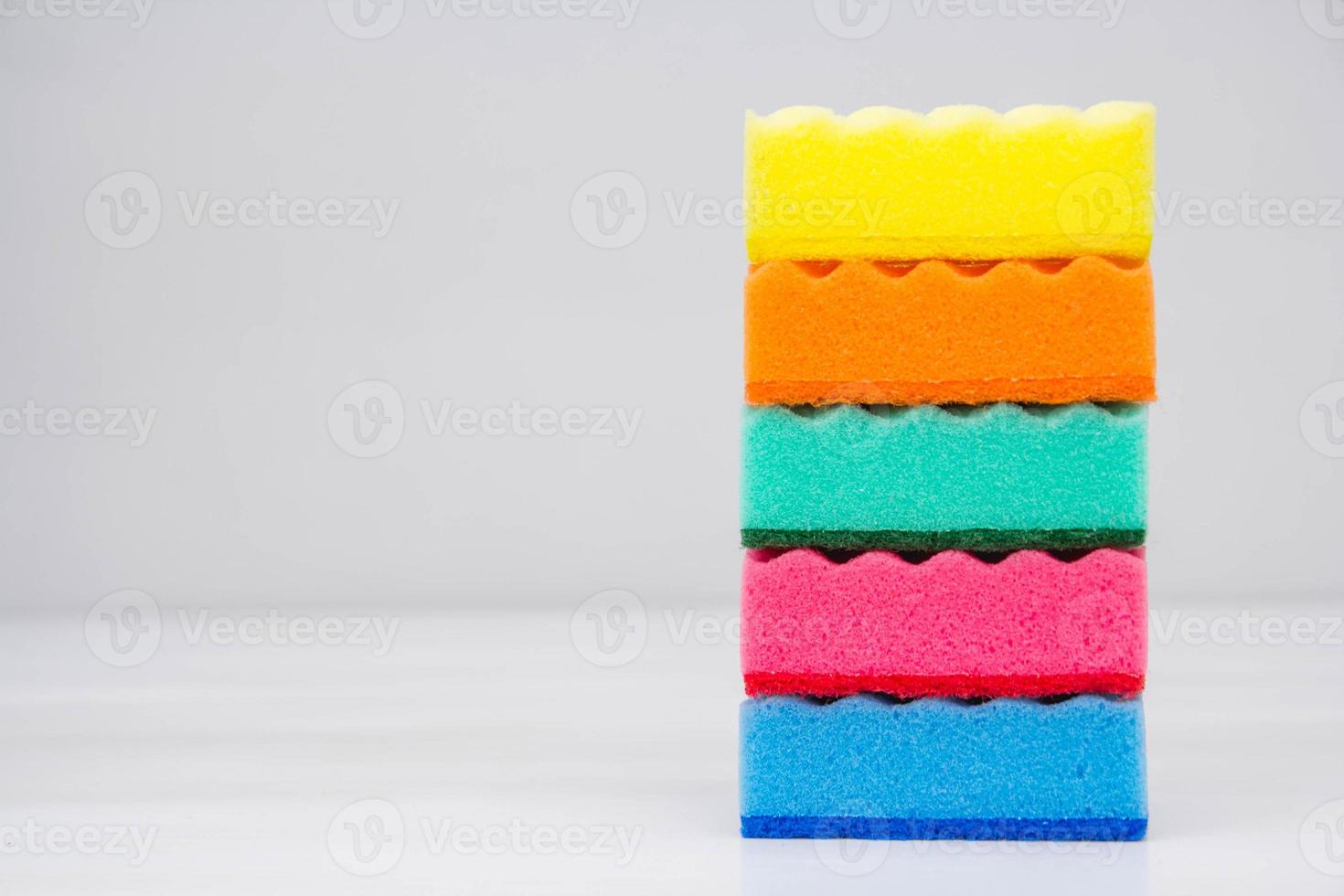 esponjas multicoloridas para limpar e lavar pratos em uma mesa branca foto