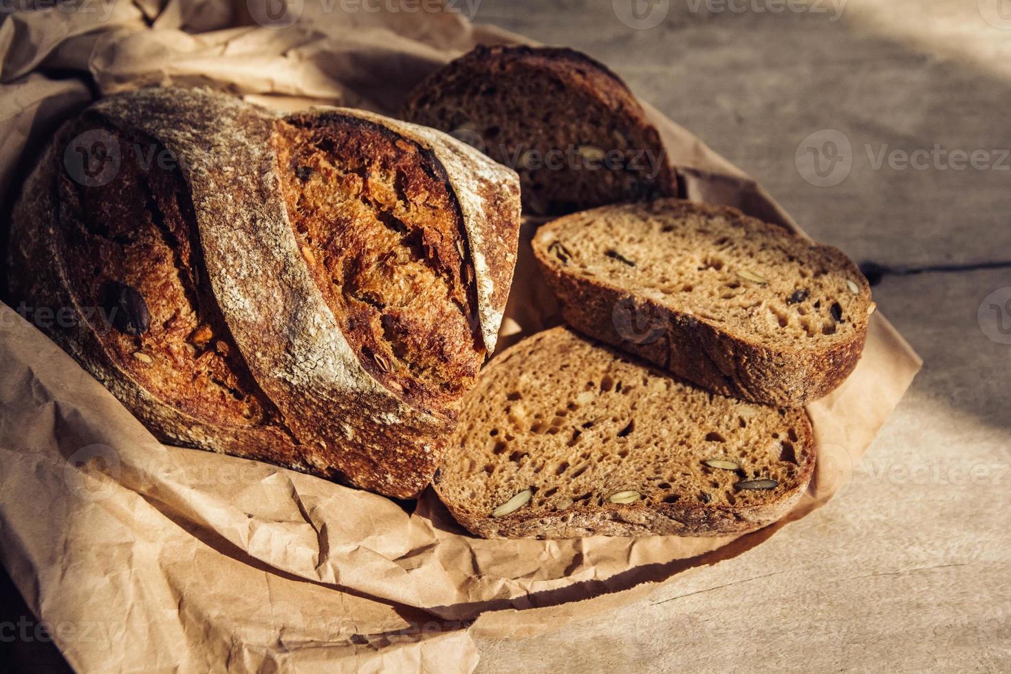 fatias de pão integral com sementes são cortadas em pedaços em um fundo de madeira velha foto