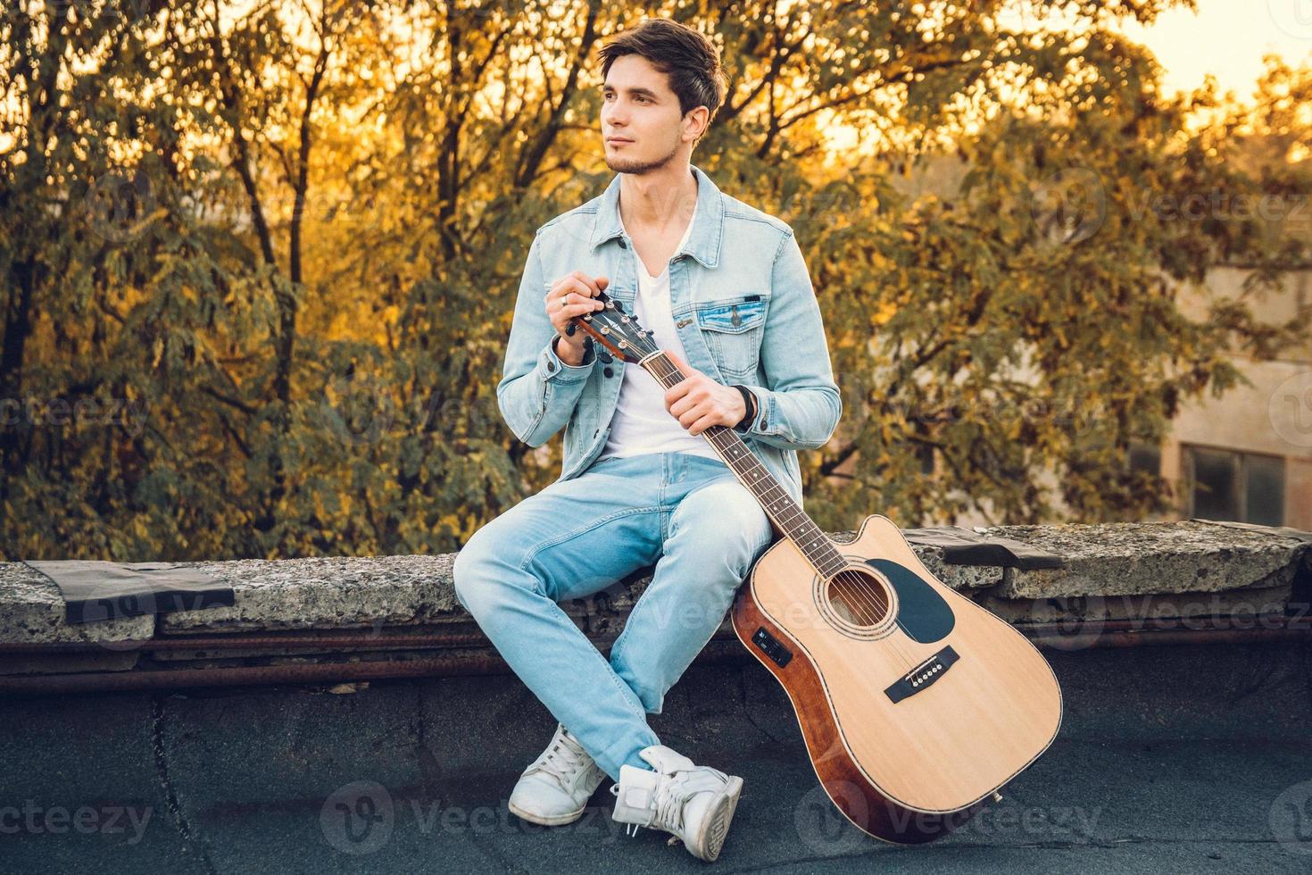 jovem segurando uma guitarra na cidade em fundo de raios de sol foto