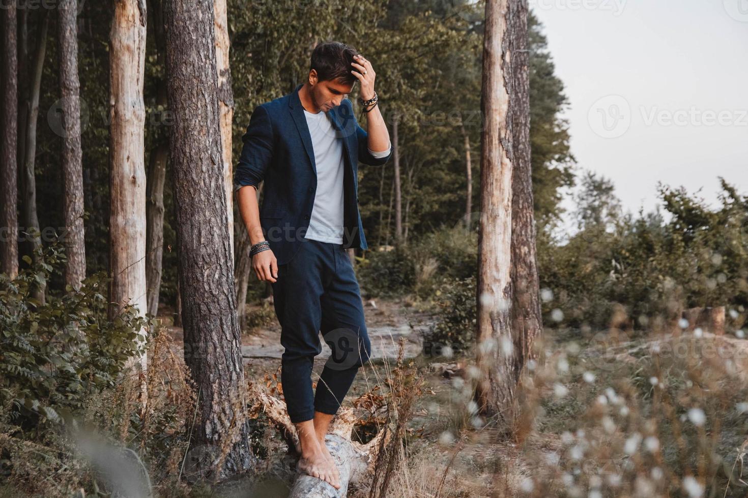 homem posando ao ar livre na floresta fica descalço em um tronco foto