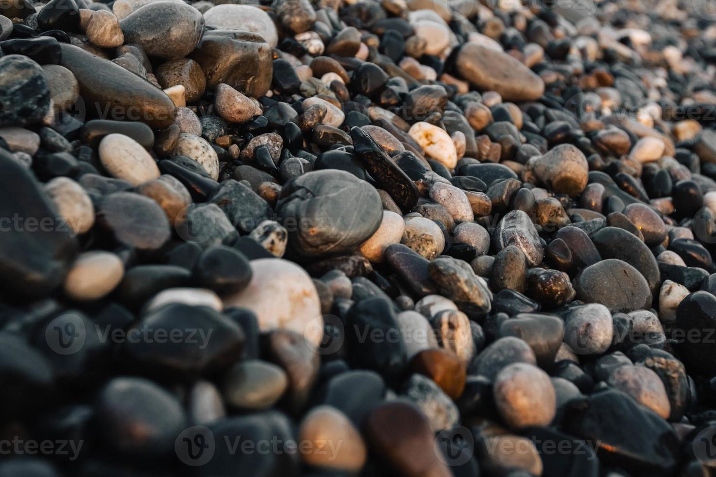 pequenas pedras à beira-mar com efeito bokeh. fundo decorativo desfocado, lugar para texto. papel de parede de verão, luz do sol ensolarada foto