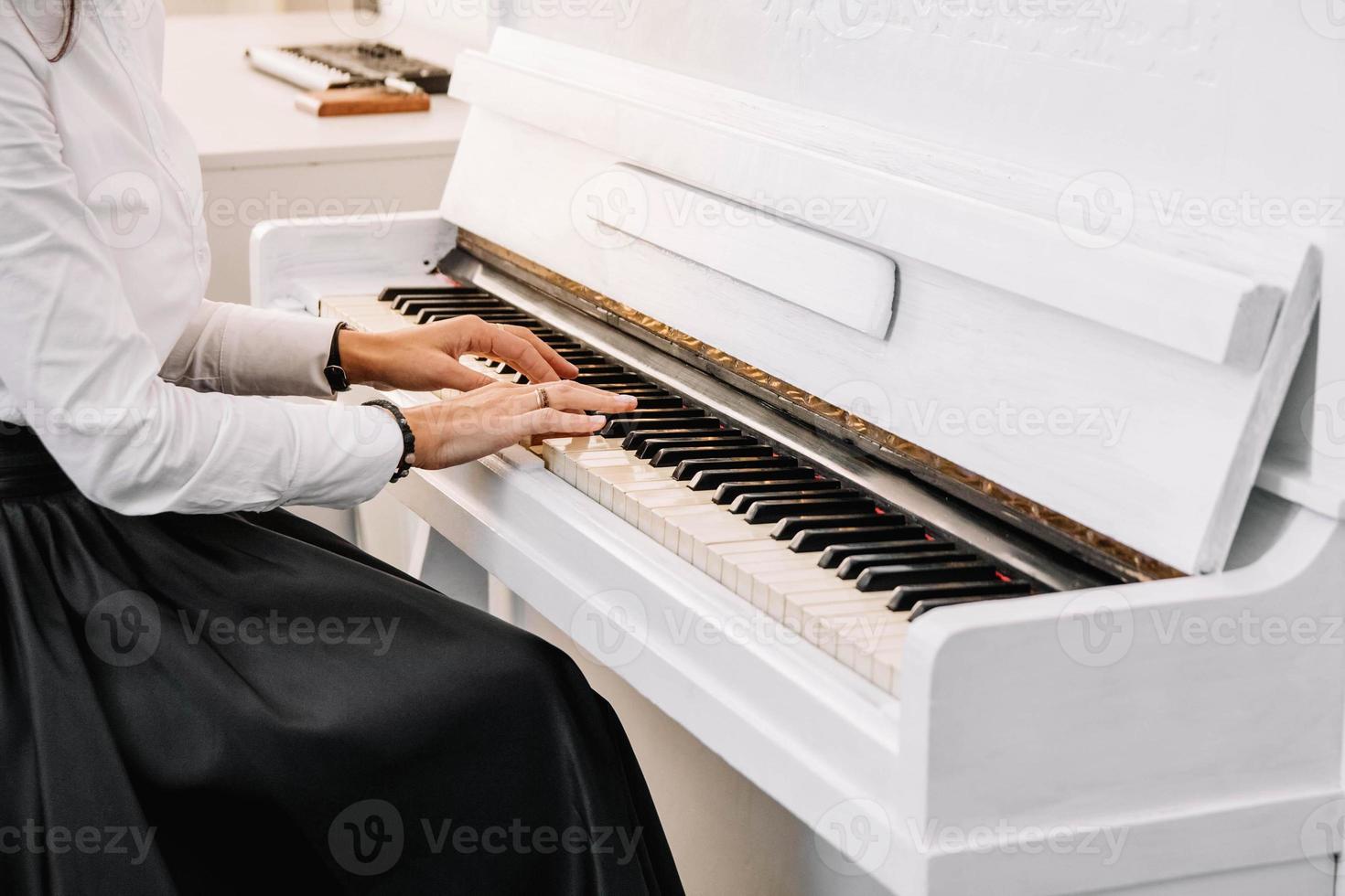 linda mulher vestida de vestido branco tocando piano branco foto