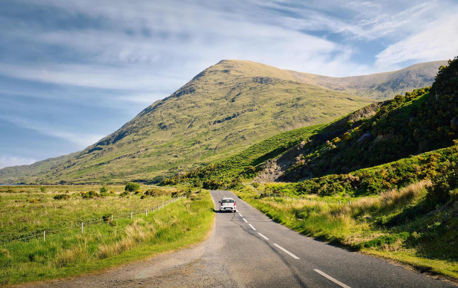lindo panorama cenário com branco carro dirigindo em esvaziar cênico estrada cocho natureza e montanhas às Delfos, município maionese, Irlanda foto
