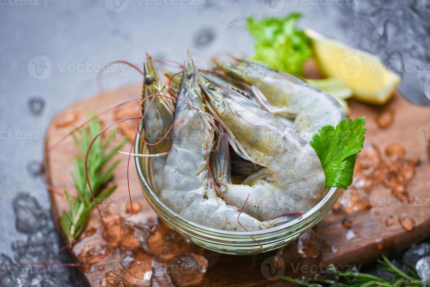 camarão fresco na tigela e tábua de madeira com ingredientes de alecrim ervas e especiarias para cozinhar frutos do mar - camarões crus camarões no gelo congelados no restaurante de frutos do mar foto