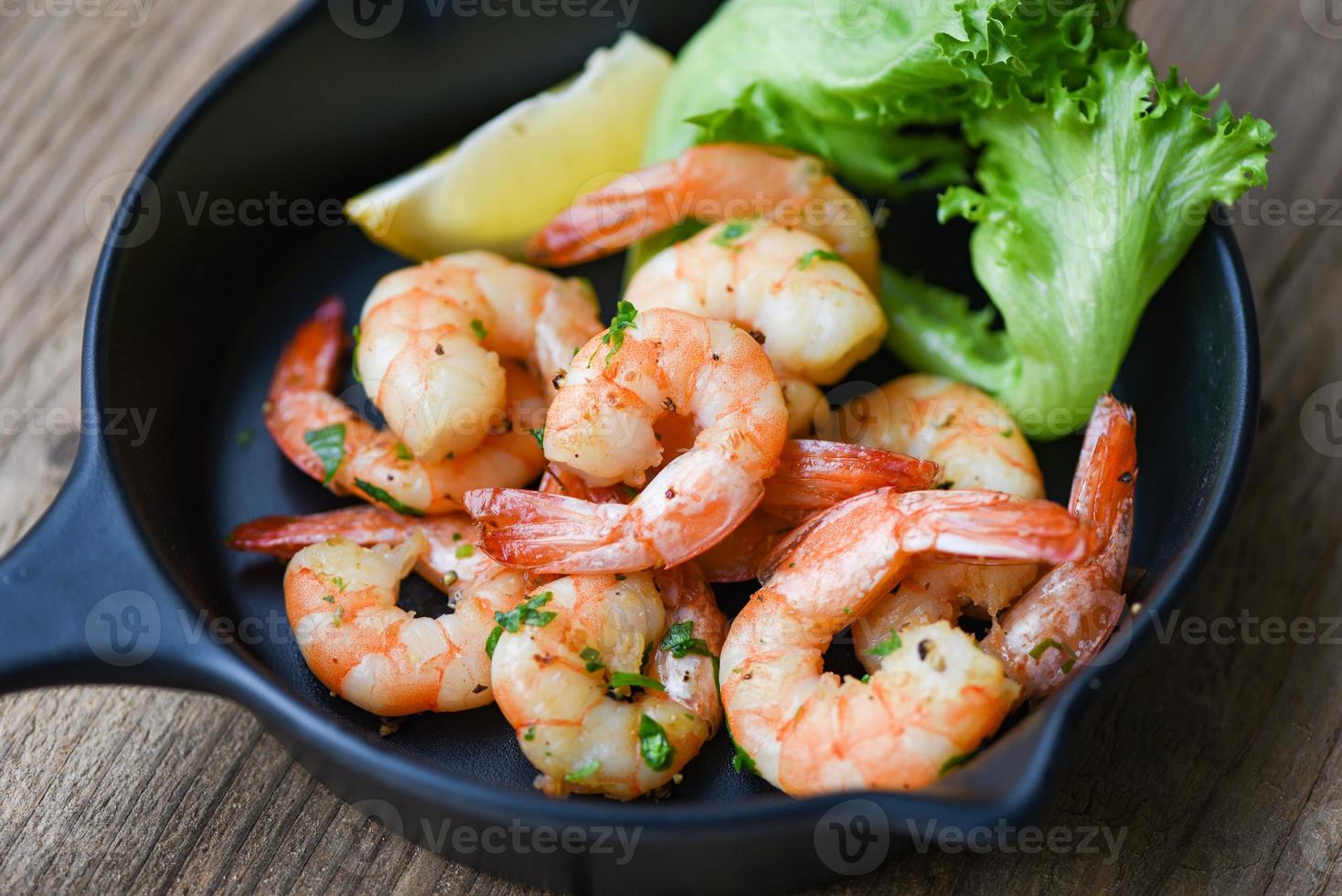 Salada de camarão grelhado com temperos deliciosos temperos na tigela - camarões cozidos apetitosos camarões assados, frutos do mar prateados com limão e alface foto