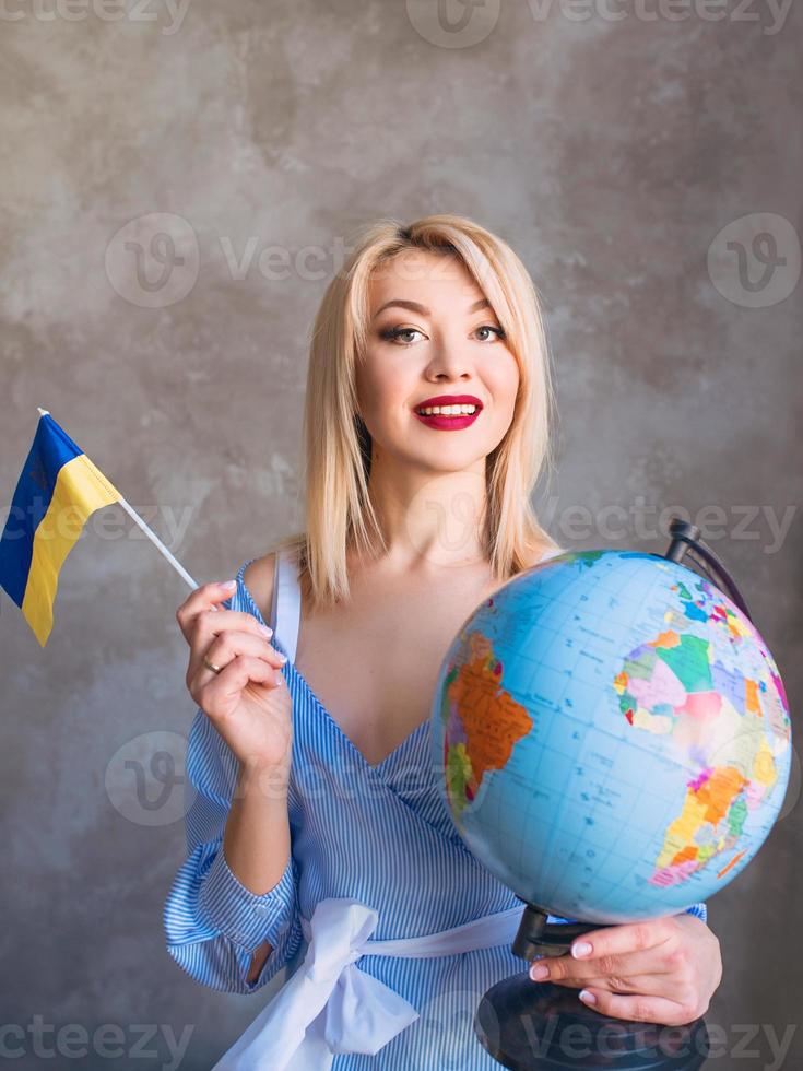 bela atraente alegre loira eslava mulher segurando o globo e a bandeira ucraniana. foto