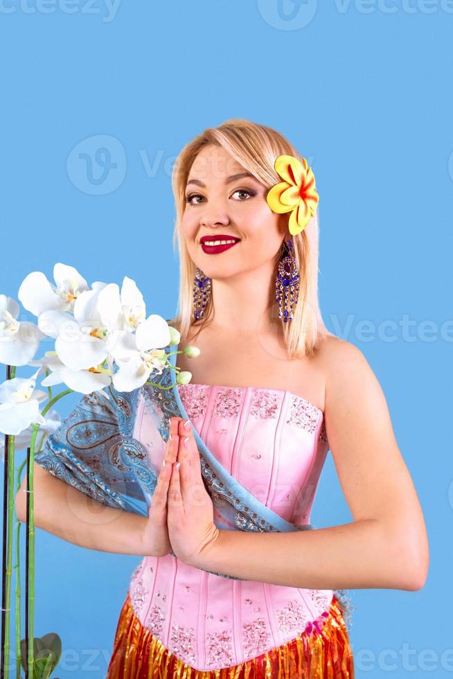 retrato de mulher europeia loira alegre em vestido nacional da Tailândia, mãos namaste foto