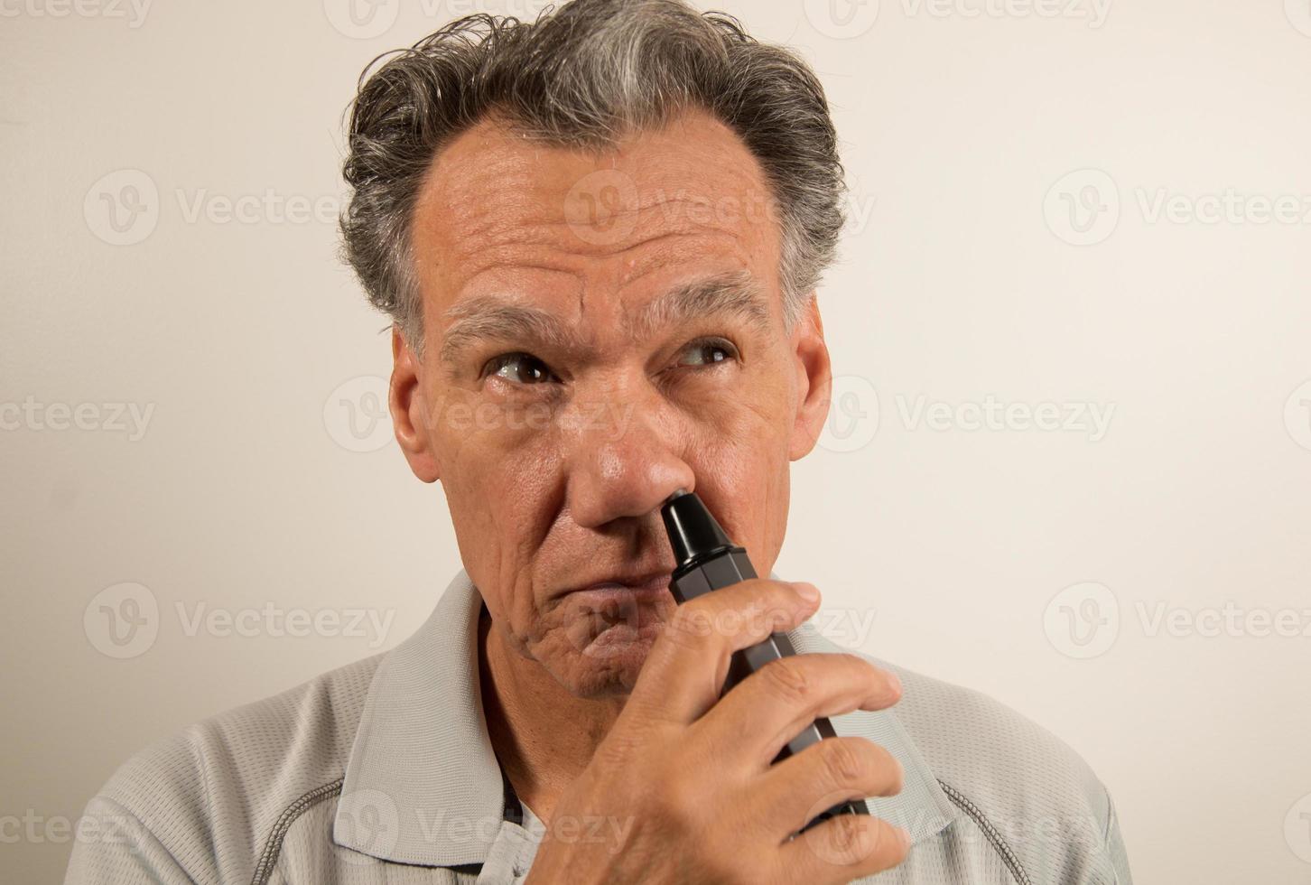 homem aparando os pelos do nariz com um aparador de pelos do nariz foto