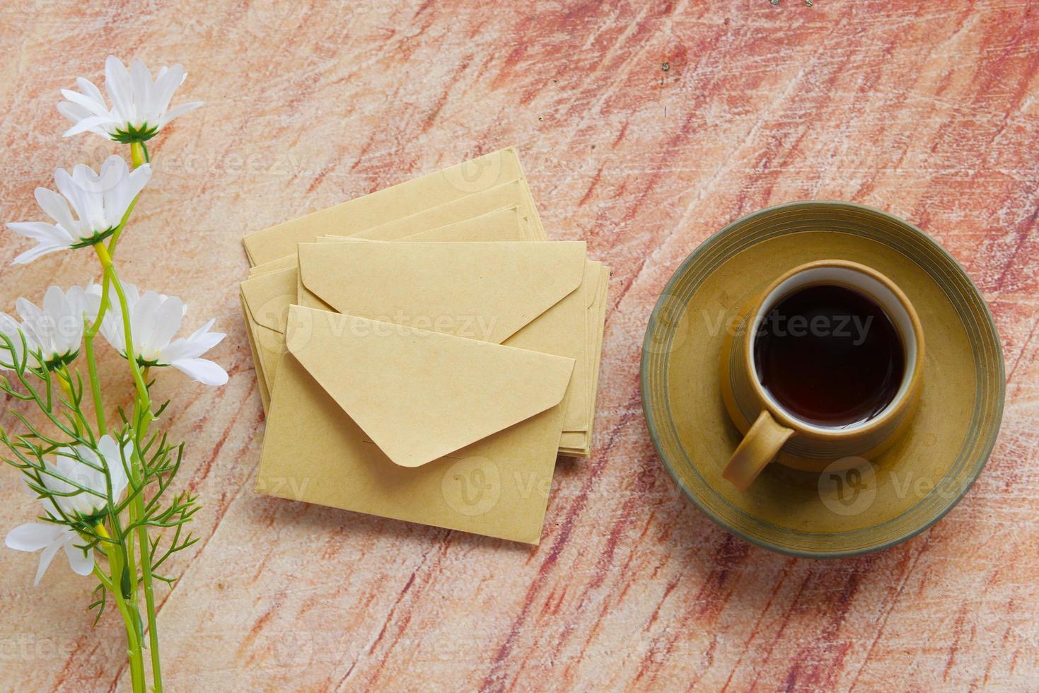 muitos envelope, xícara de chá e flores na mesa foto