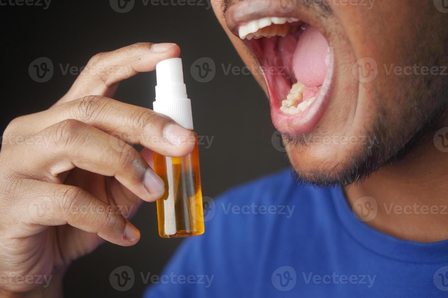 jovem homem aplicando fresco respiração spray foto
