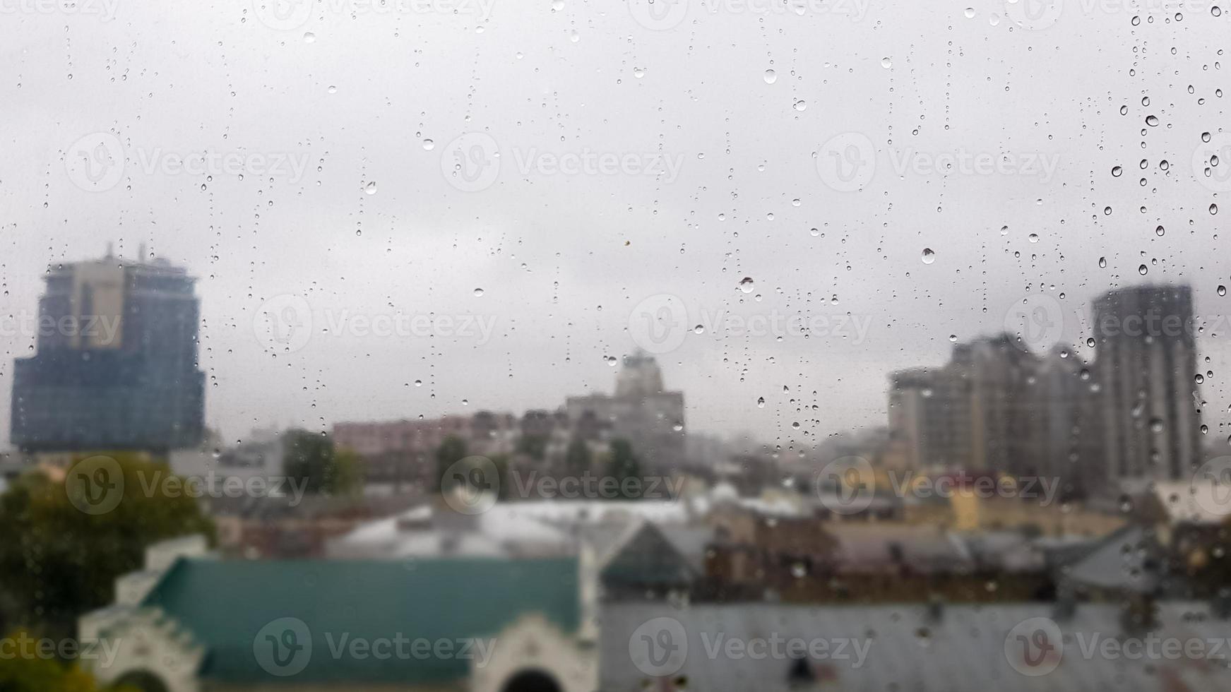 janela molhada com gotas no fundo da cidade outono em tempo nublado. vista da janela na chuva. gota d'água na janela de vidro durante a chuva com fundo desfocado da cena da cidade foto