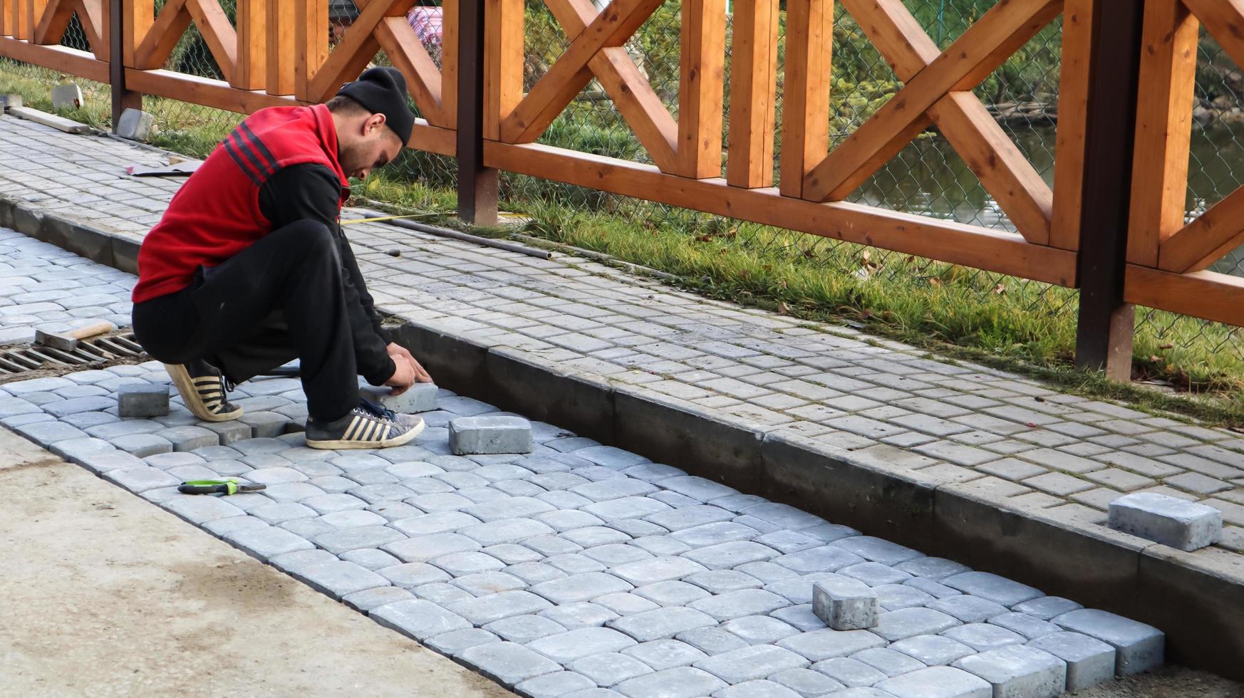 ucrânia, kiev - 12 de maio de 2020. colocação de lajes cinzentas na praça da cidade, reparo da calçada. pedreiros profissionais instalam novos ladrilhos em uma base de areia forrada. foto