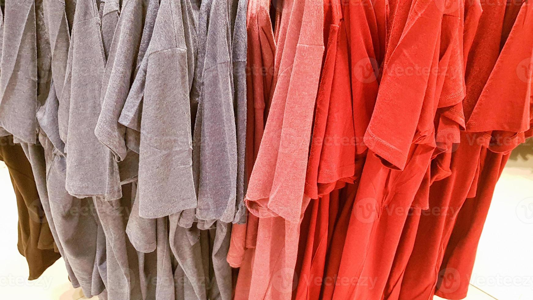 cores do arco-íris. variedade de camisas casuais, camisetas em cabides em uma loja. pano de algodão de várias cores brilhantes close-up. fundo têxtil foto