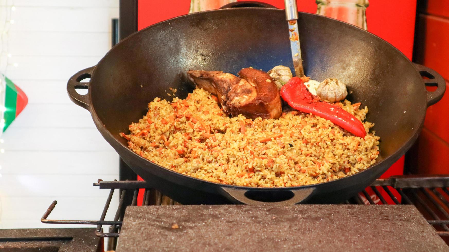 delicioso uzbeque pilaf em um caldeirão ao ar livre em um festival de comida de rua. cozinhar arroz com carne e vegetais. uma grande panela de culinária cazaque nacional na rua durante o festival. foto