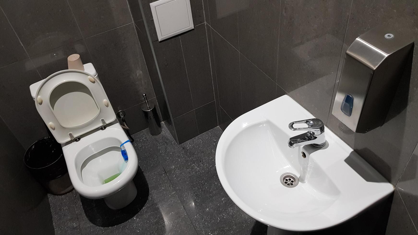 lavatório de cerâmica branca com torneira cromada no vaso sanitário com telha cinza foto