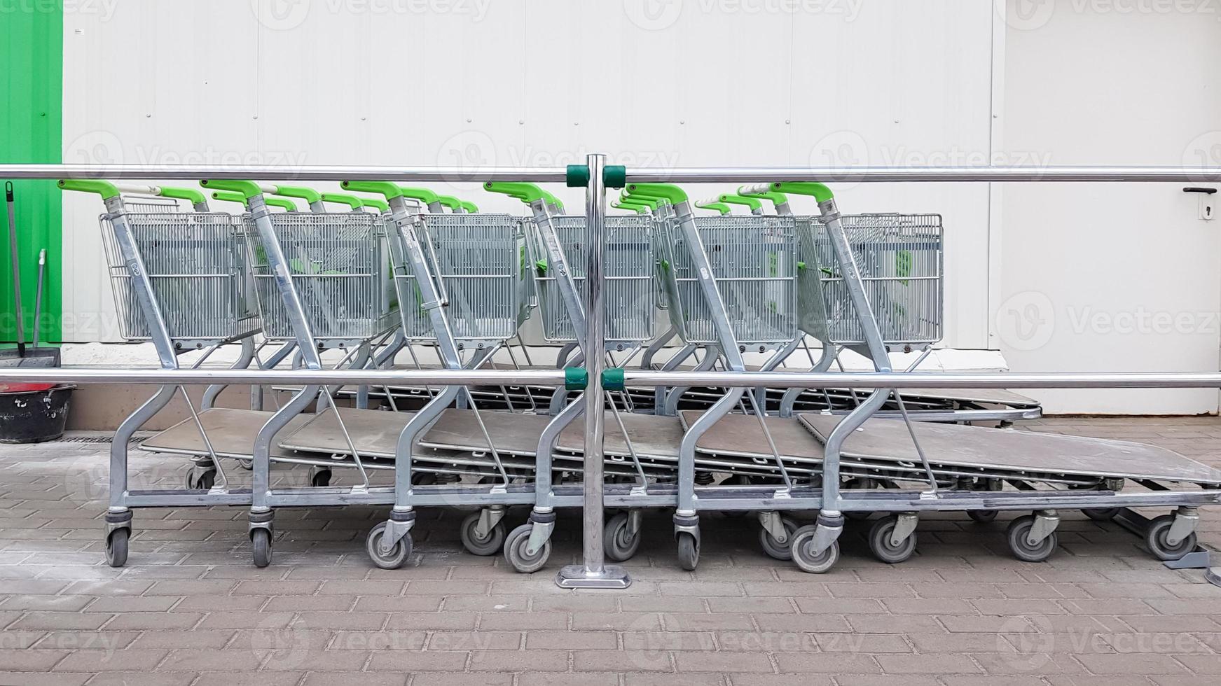 muitos carrinhos de metal estão estacionados em uma fileira perto de um supermercado de construção ao ar livre. conceito de negociação. foto