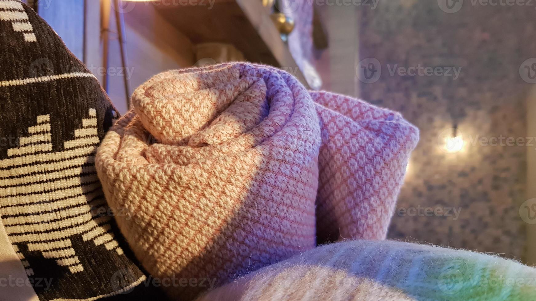 cobertores de malha e quentes são dobrados e colocados em uma cesta de vime perto da lareira. interior aconchegante da casa. detalhes de um interior moderno e aconchegante foto
