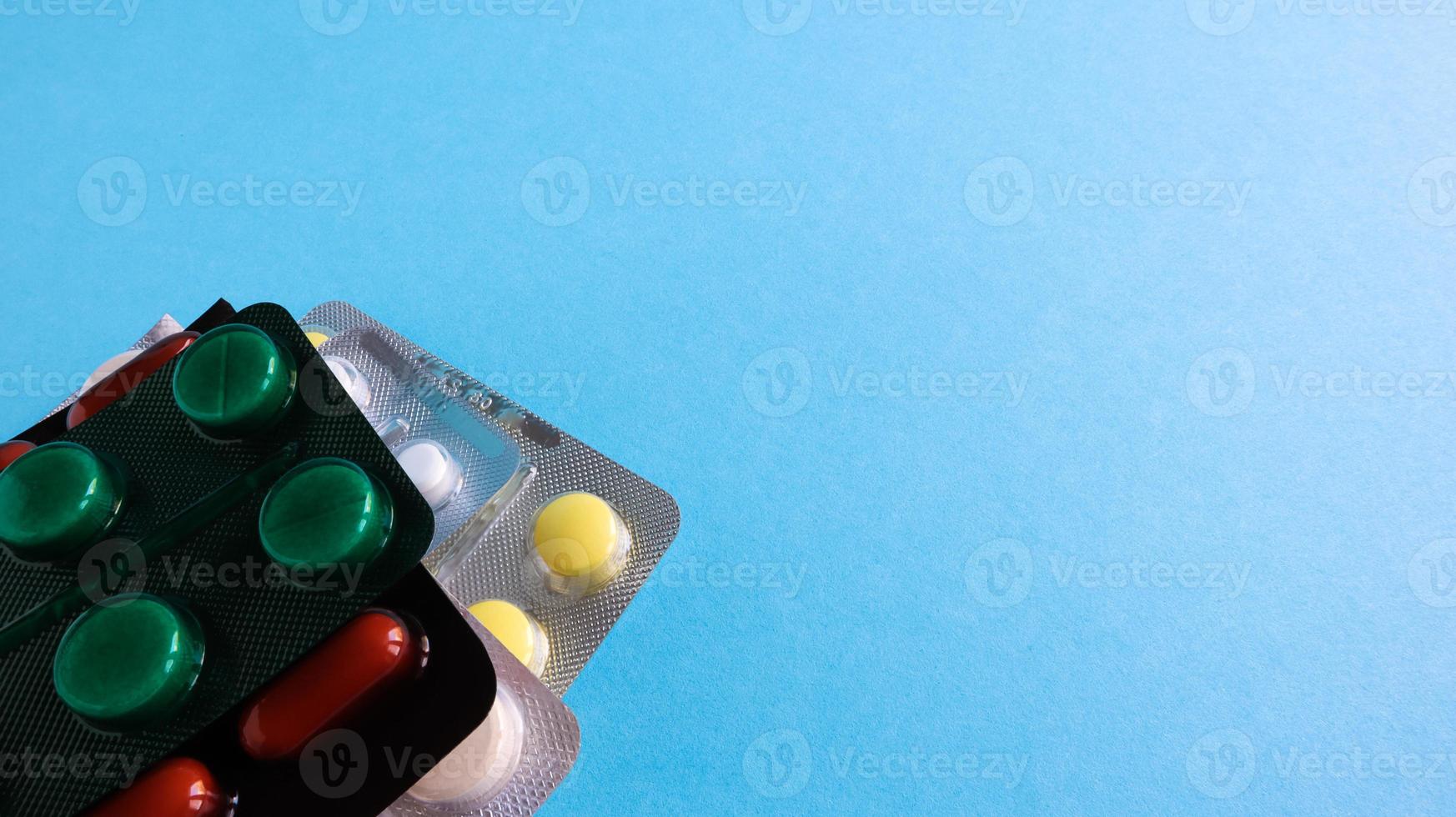 pacotes de comprimidos de várias formas e cores estão empilhados sobre um fundo azul. as cápsulas são embaladas em embalagens de blister. medicamentos diferentes. tratamento medicamentoso. foto de saúde. copie o espaço.