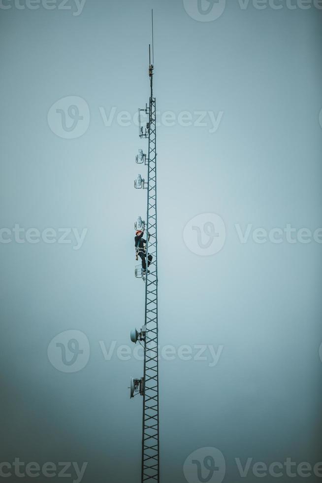 trabalhador de telecomunicações escalando torre de antena foto