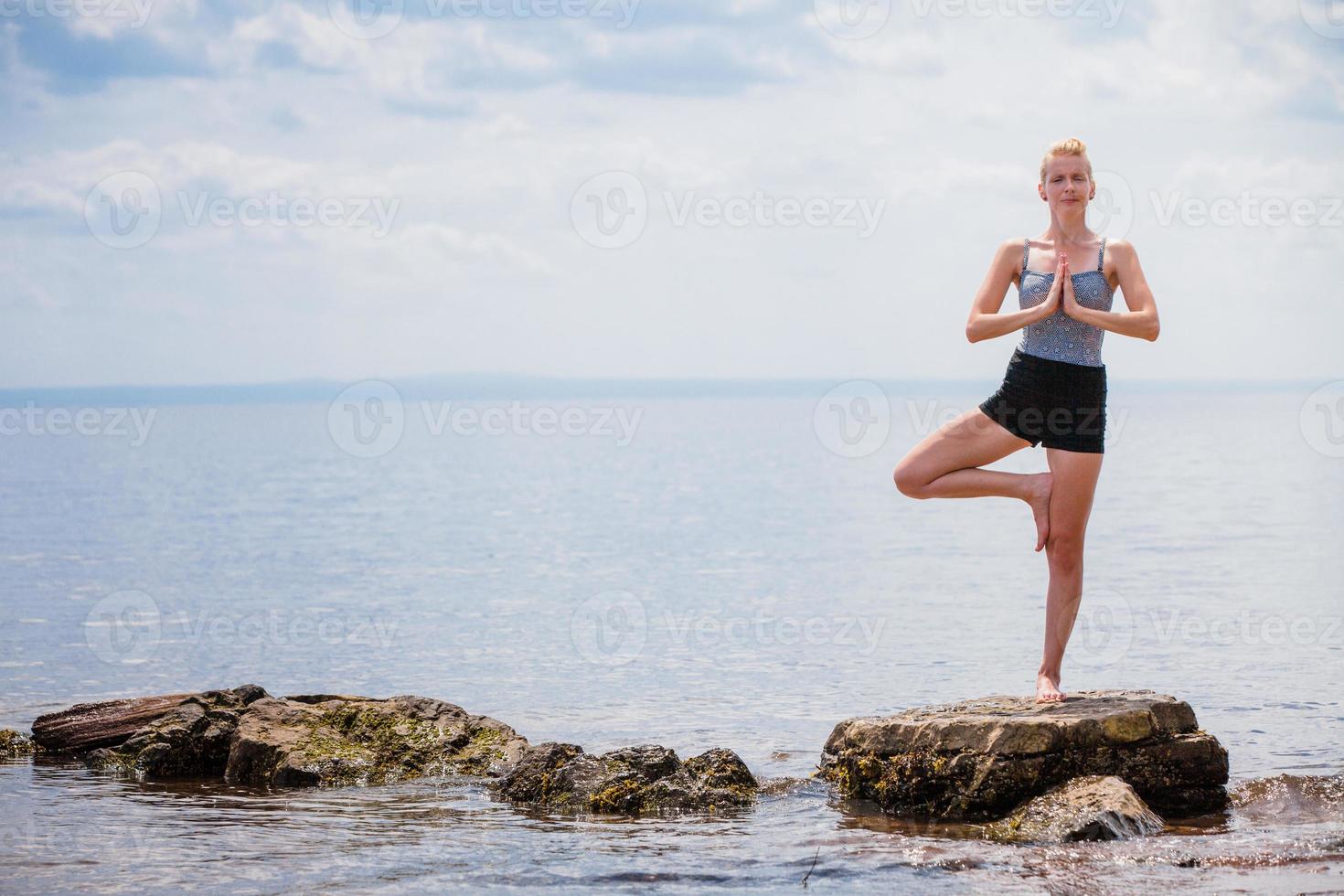 jovem fazendo ioga em posição de árvore foto