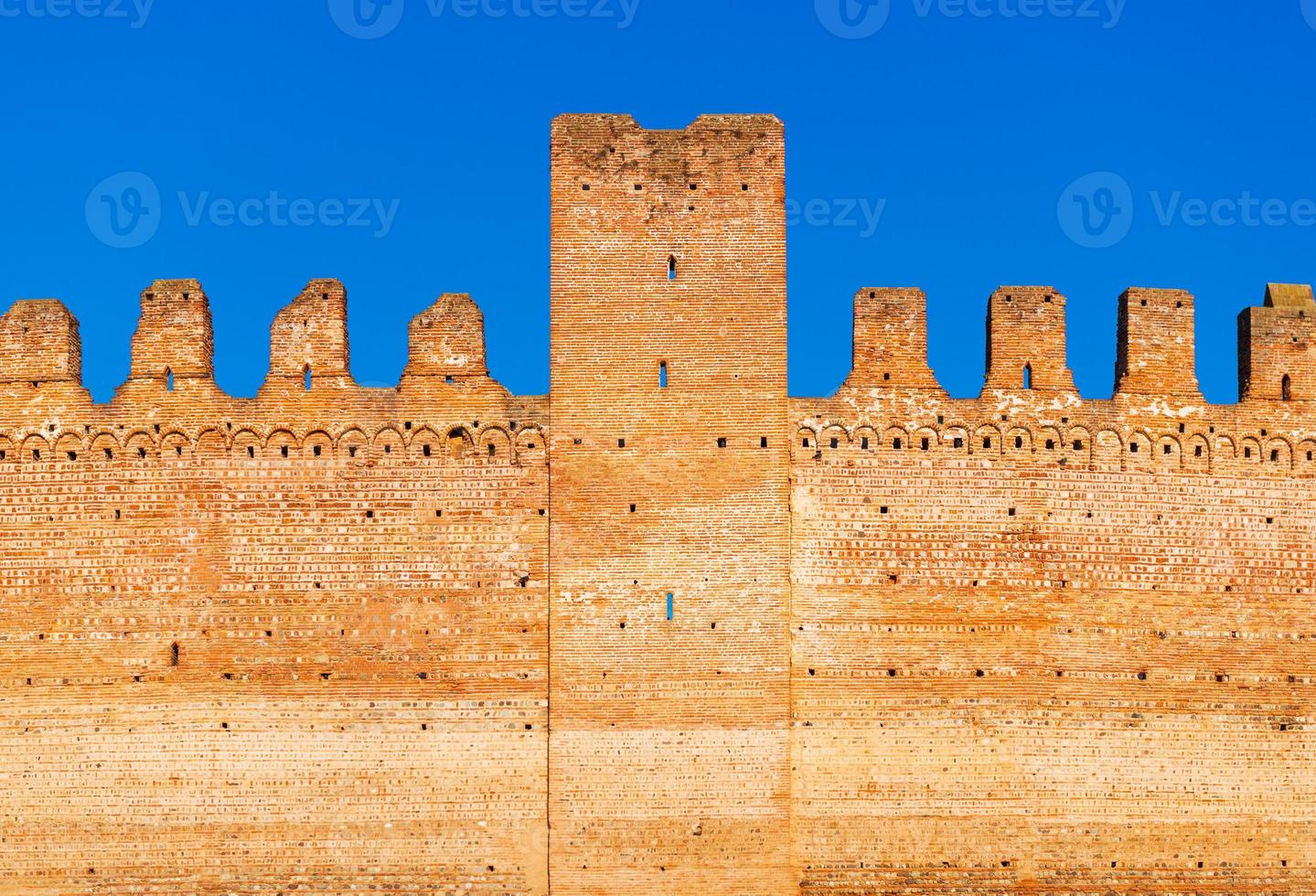 velha parede de tijolos da fortaleza medieval italiana contra o céu azul foto