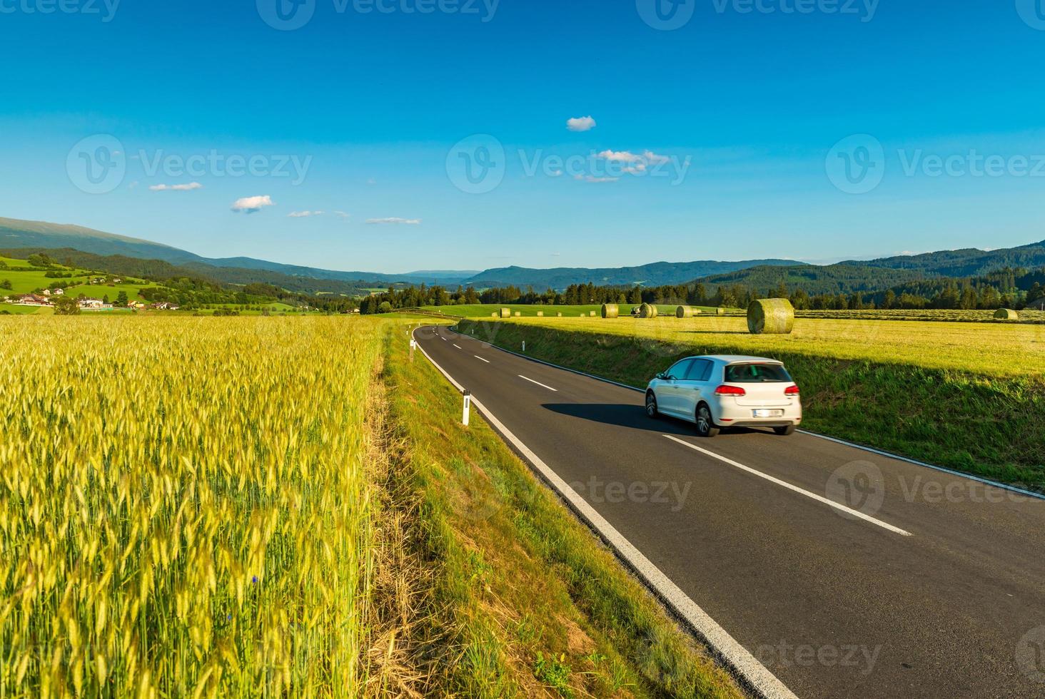 um carro branco passa por campos pitorescos em algum lugar da Áustria foto