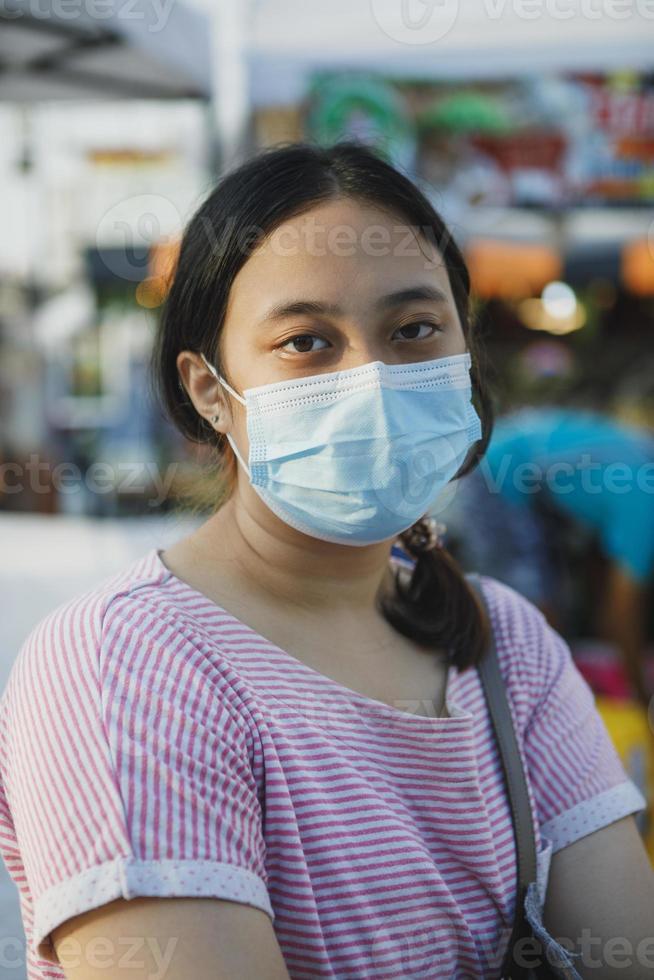 jovem asiática usando máscara protetora em pé ao ar livre foto