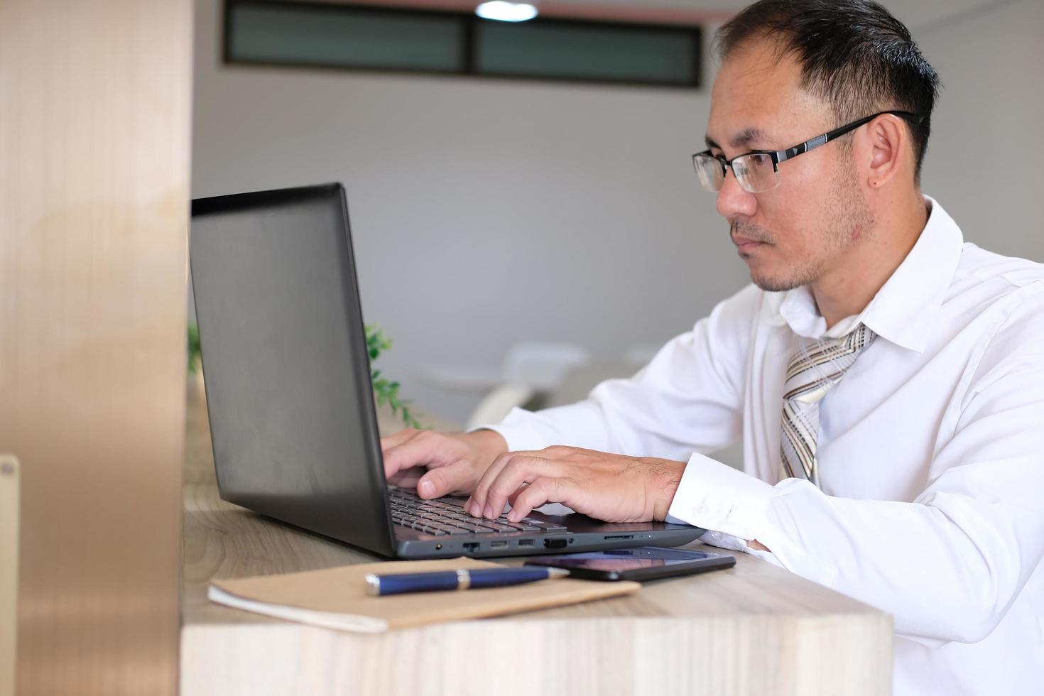 jovem empresário usando um laptop em sua mesa em um escritório moderno foto