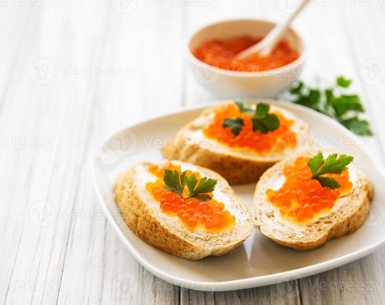 caviar vermelho na tigela e sanduíches foto