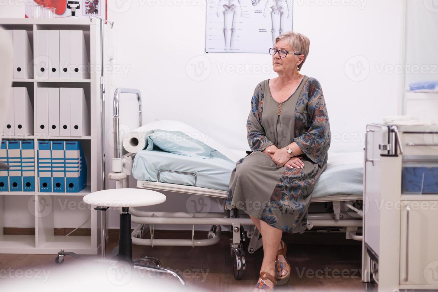 mulher idosa sentada na cama do hospital foto