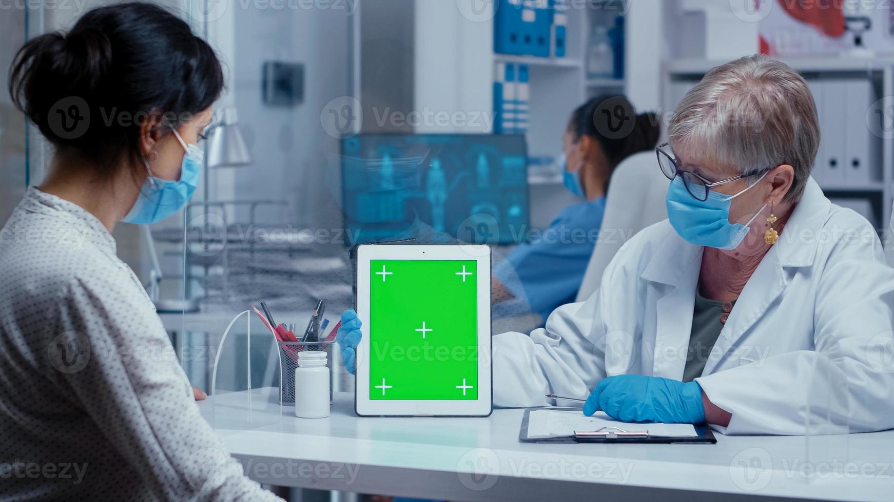 médico mostrando tablet de tela verde foto
