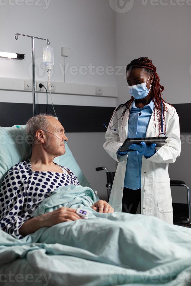 médico com máscara cirúrgica em quarto de hospital discutindo diagnóstico foto