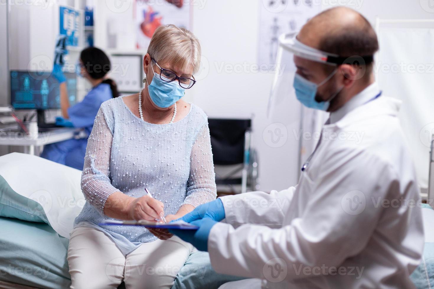 paciente idoso assina acordo médico foto