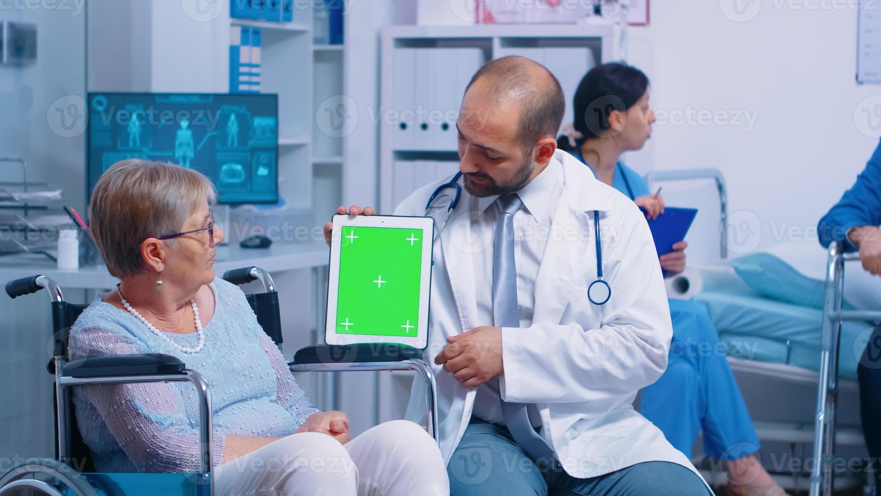 médico segurando mock-up tablet no centro de recuperação para pacientes idosos com deficiência foto