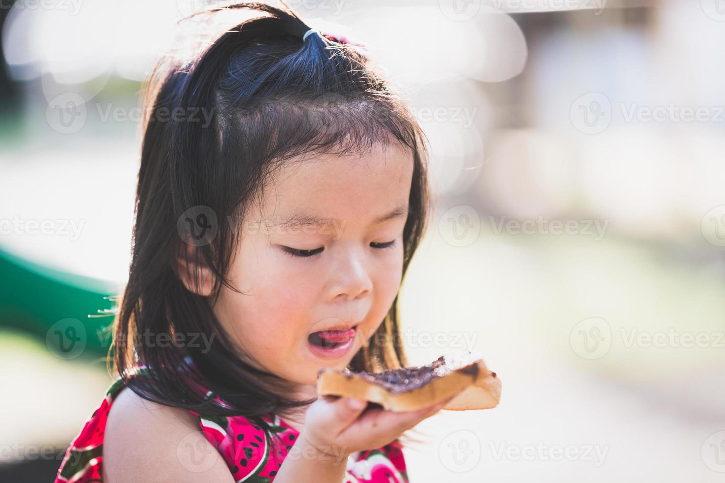 adorável menina lambendo o chocolate nos lábios. criança com pão de chocolate como lanche de piquenique. bebê de 4 anos. foto