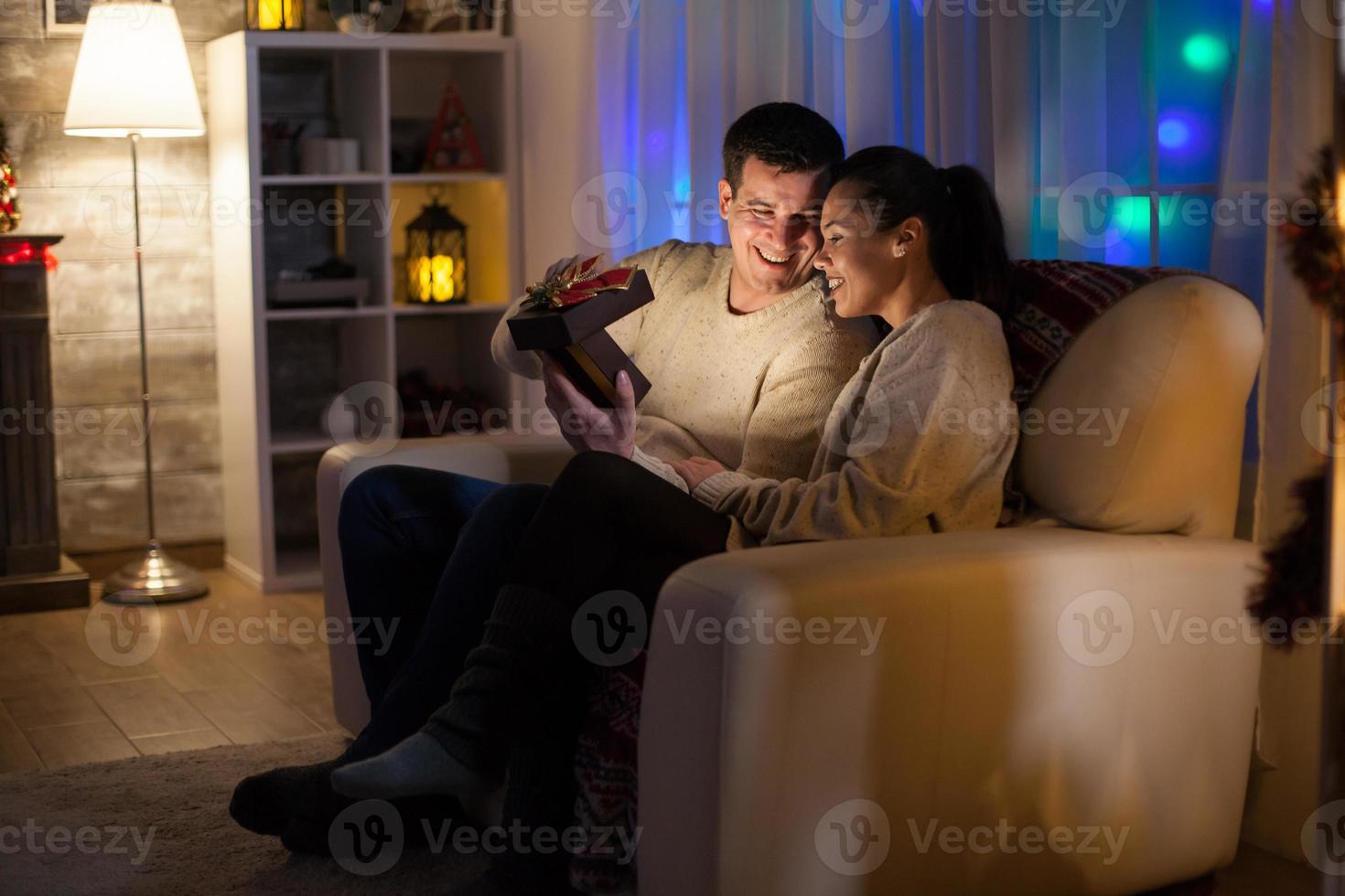 casal apaixonado no dia de natal sentado no sofá foto