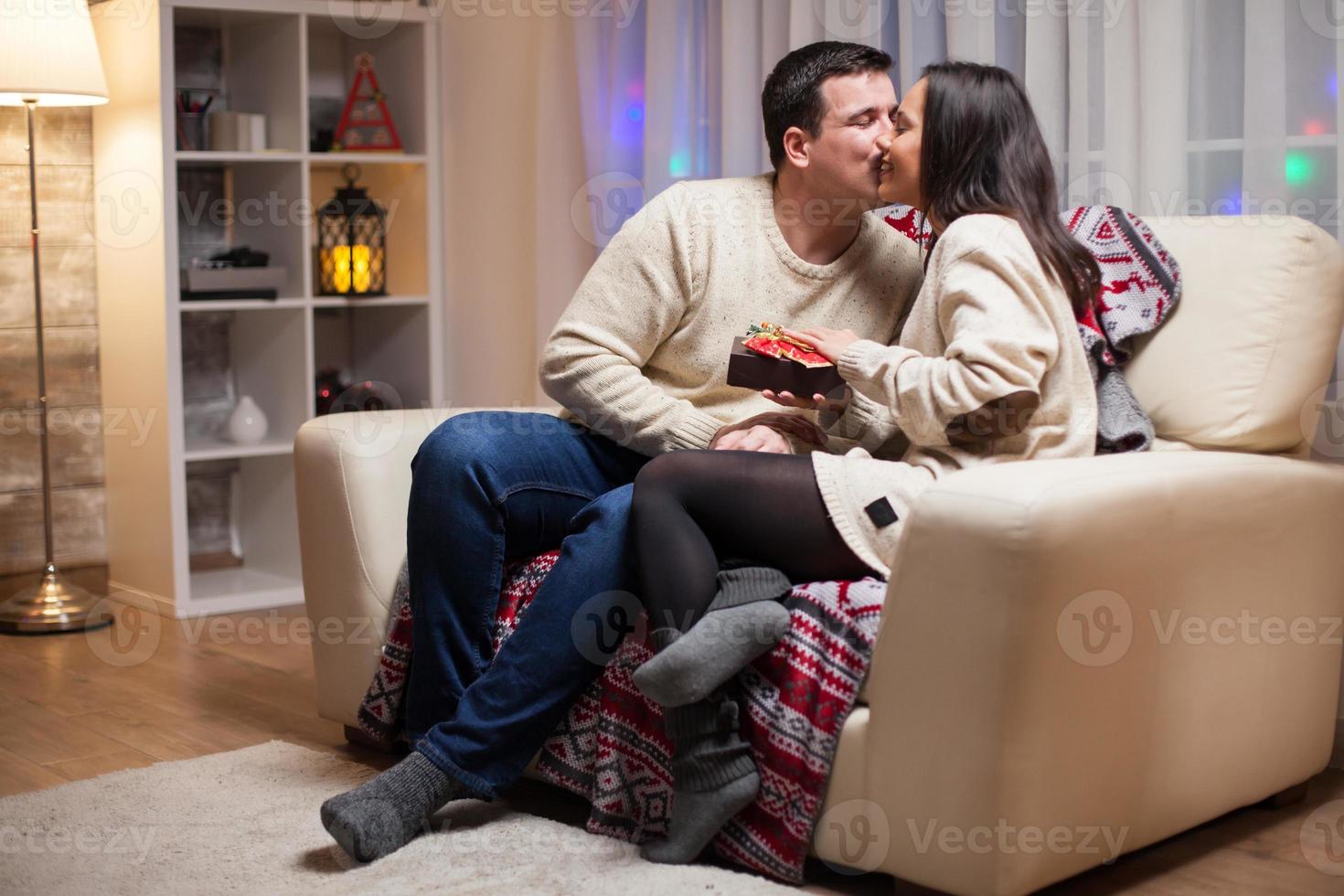 jovem beijando a bochecha da esposa no dia de natal foto