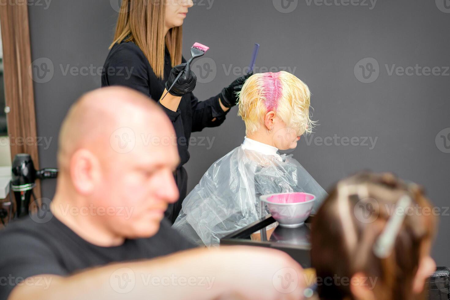 coloração fêmea cabelo dentro a cabelo salão. jovem mulher tendo dela cabelo tingido de esteticista às a beleza salão. foto