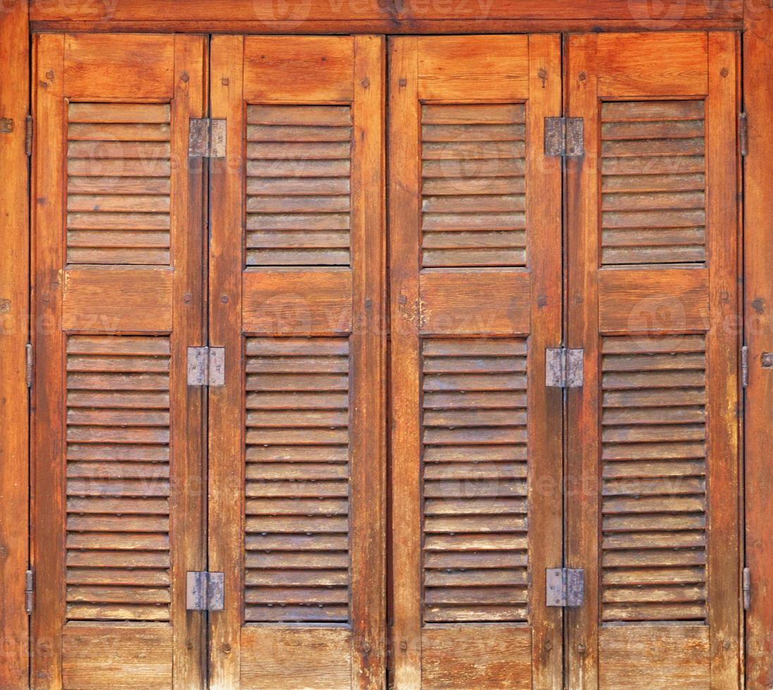 velhas janelas de madeira laranja com venezianas de madeira e dobradiças de metal no estilo grego. foto