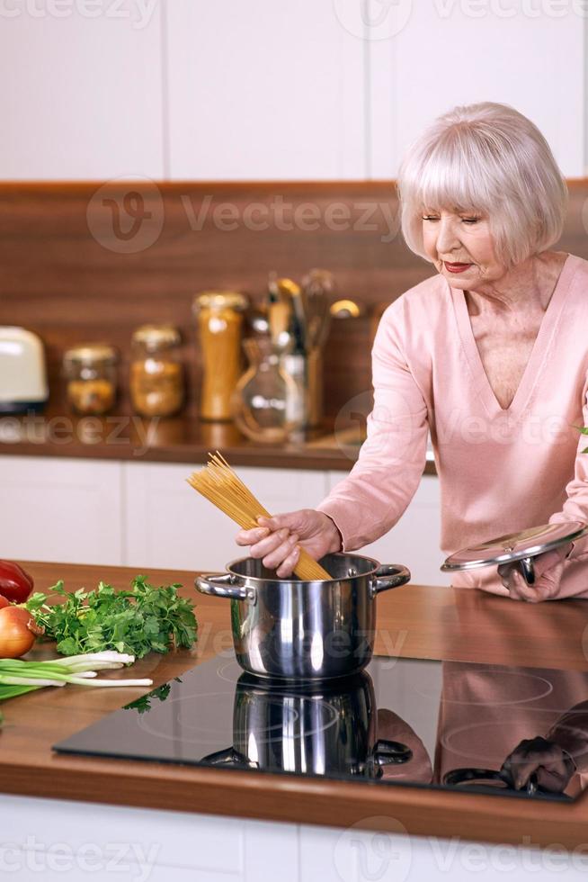 mulher alegre sênior está cozinhando na cozinha moderna. alimentos, habilidades, conceito de estilo de vida foto