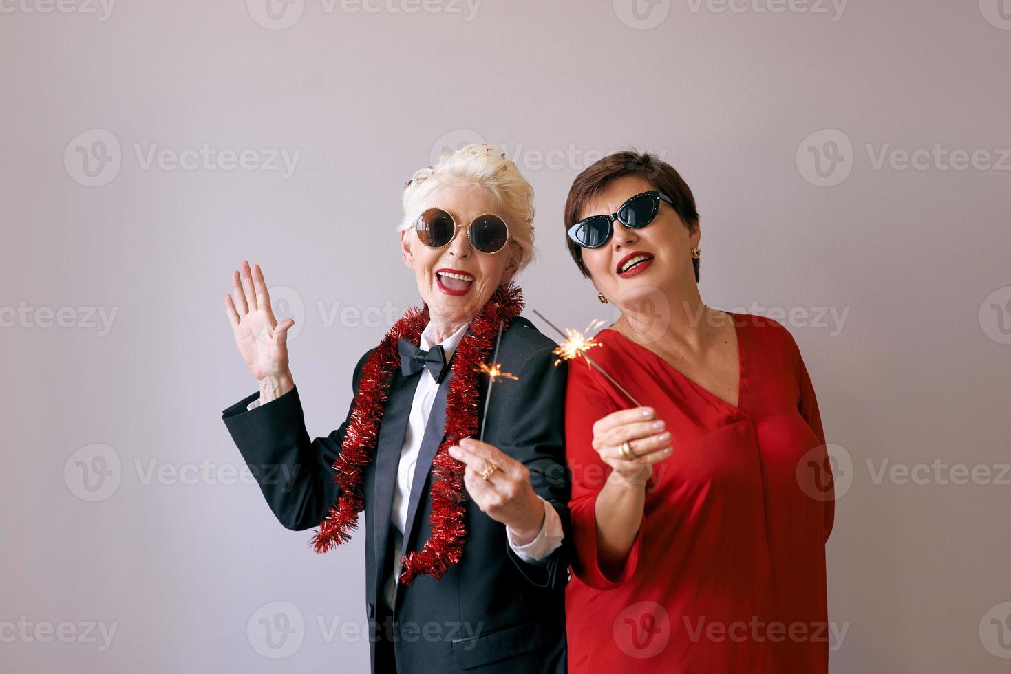 duas belas elegantes mulheres maduras sênior em óculos de sol, comemorando o ano novo. diversão, festa, estilo, conceito de celebração foto