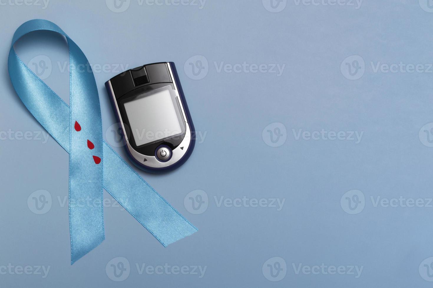 close-up vista superior do conceito para o diabetes mundial dia 14 de novembro. fita azul com gotas de sangue e um glicosímetro em um fundo azul foto