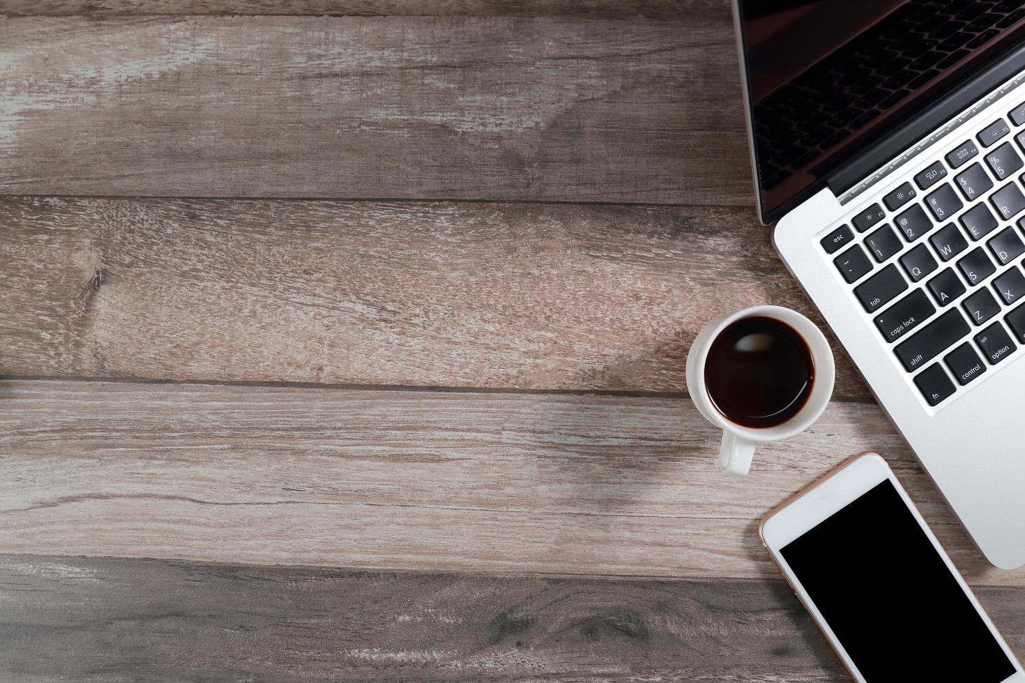 mesa de escritório de madeira com computador e telefone inteligente com xícara de café foto