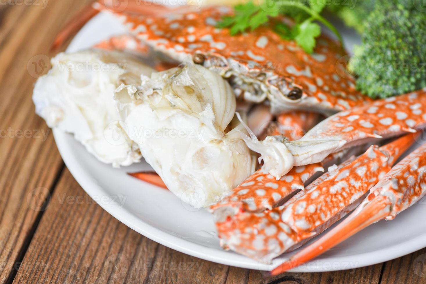 carne de caranguejo - garras e patas de caranguejo cozidas em um prato branco e molho de frutos do mar na mesa, caranguejo nadador azul foto