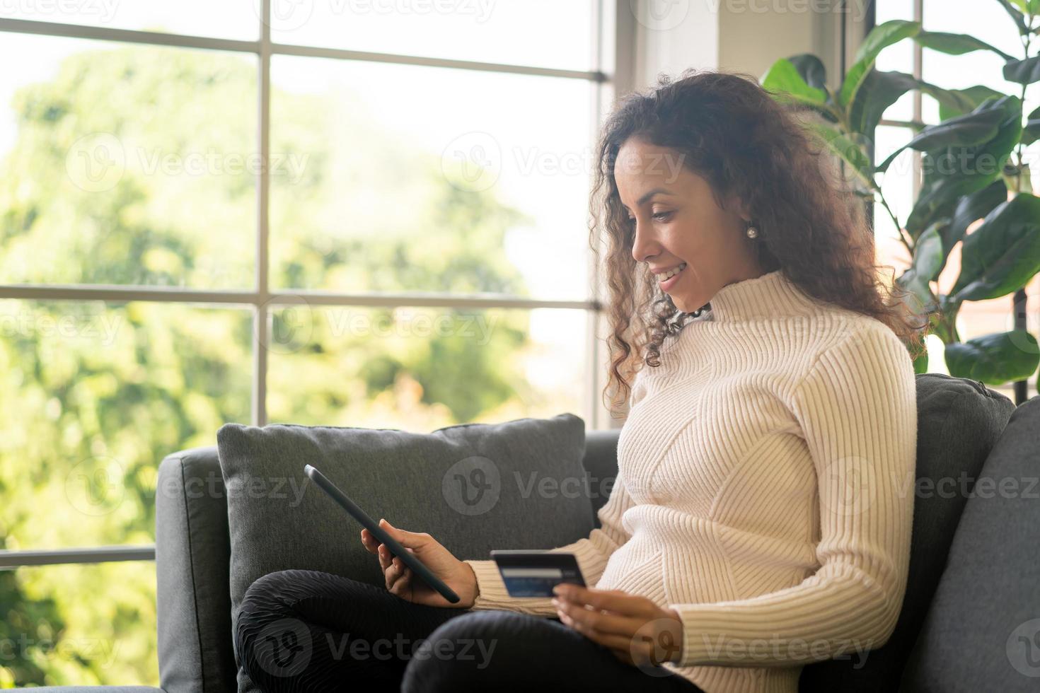 mulher latina usando tablet e mão segurando cartão de crédito foto