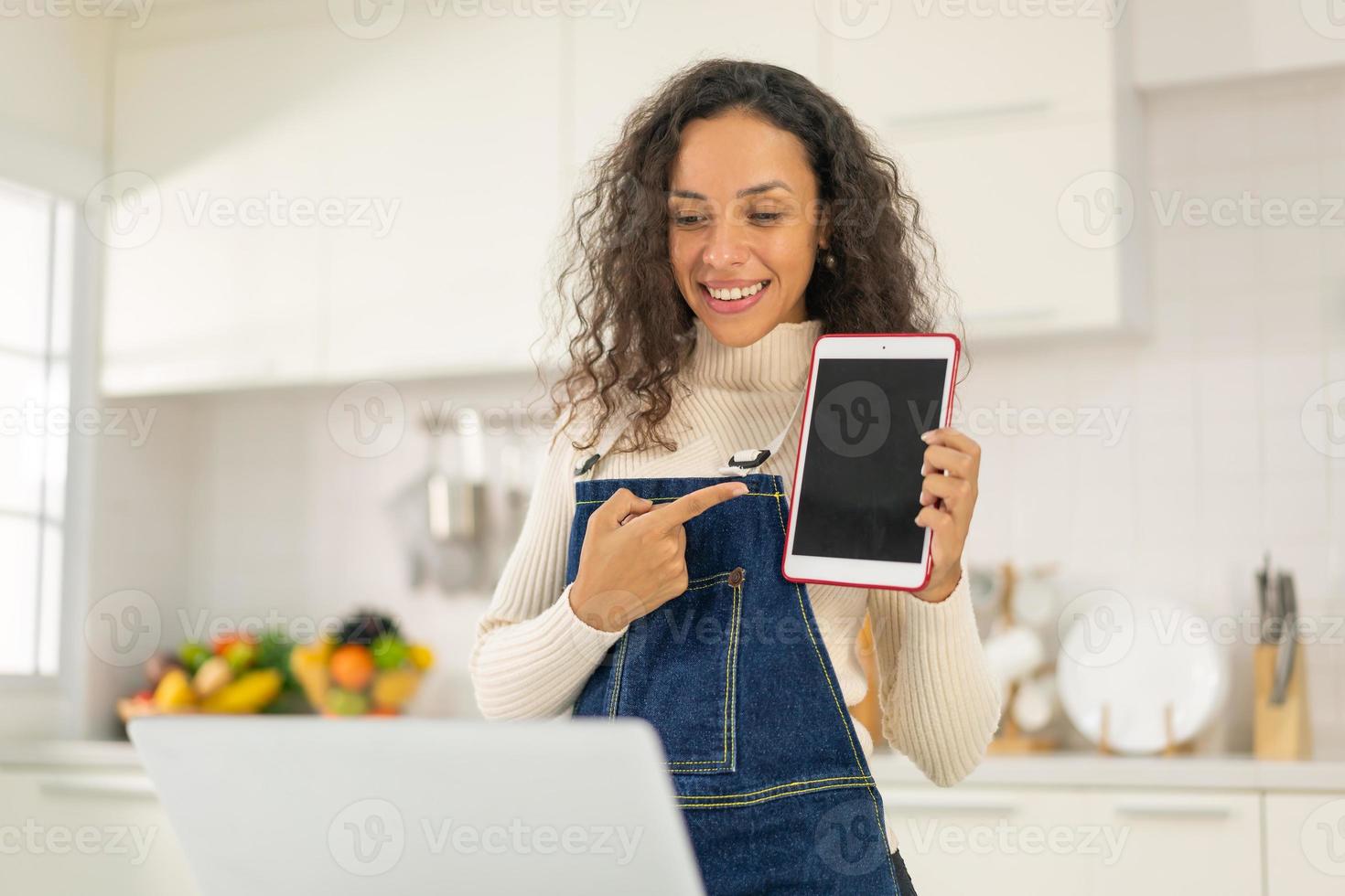 mulher latina gravando vídeo e cozinhando na cozinha foto