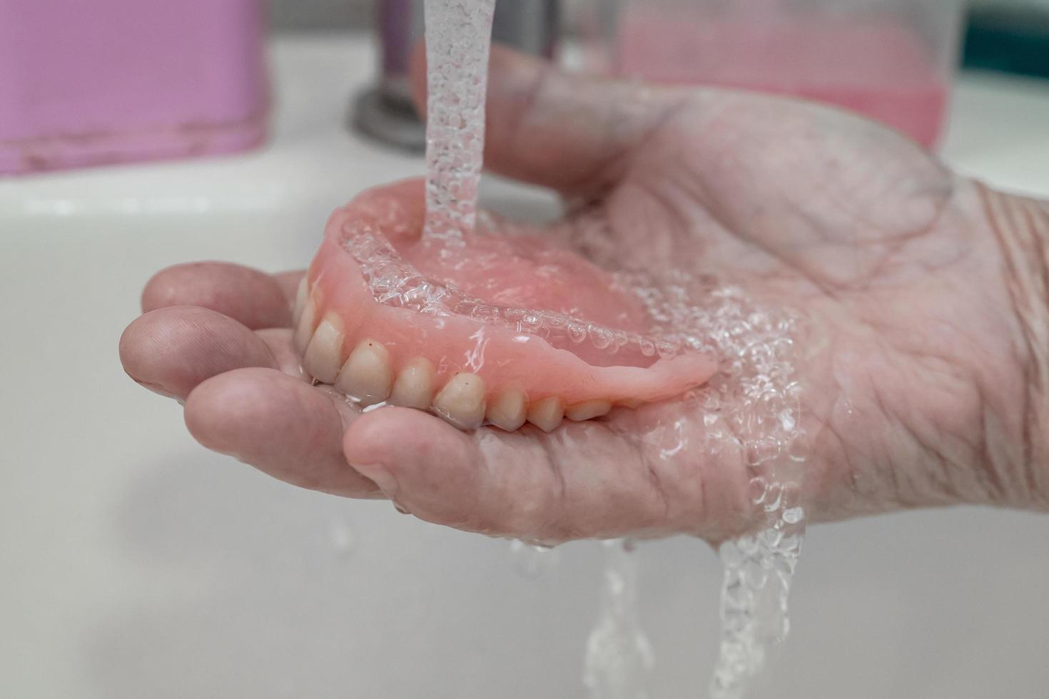 paciente asiático sênior ou idosa segurando prótese parcial de dentes de substituição. foto