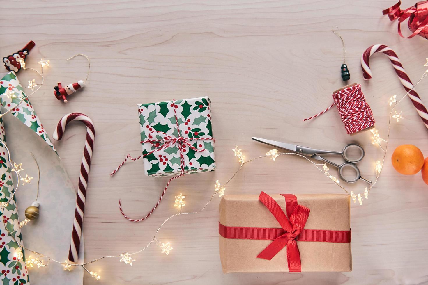 composição de natal. caixas de presente, presentes de embrulho com papel e fita, luzes, bastões de doces em fundo de madeira. decoração de casa artesanal de diy holdiay. inverno, ano novo plano horizontal, vista de cima foto